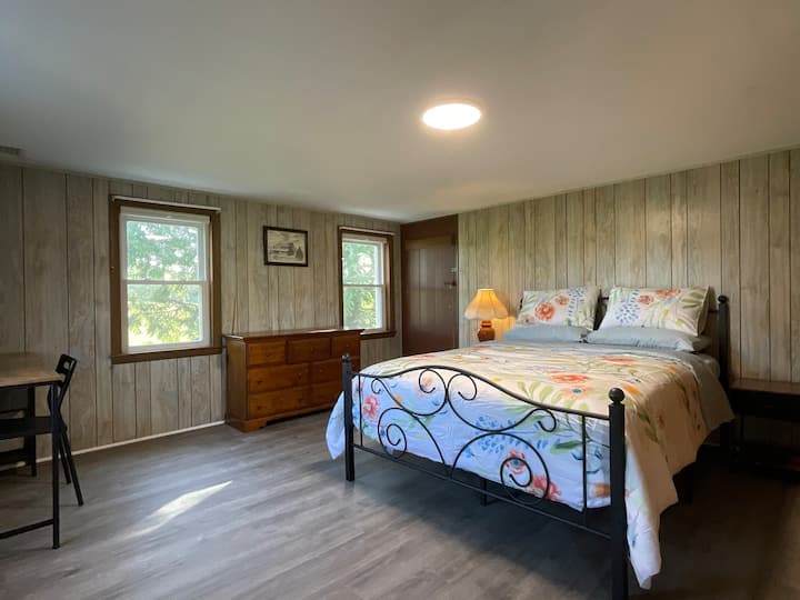 Dormitorio 1. Cama tamaño queen, dos armarios, una mesa de computadora. Las ventanas en dos lados dan al lado sur y este de la granja.