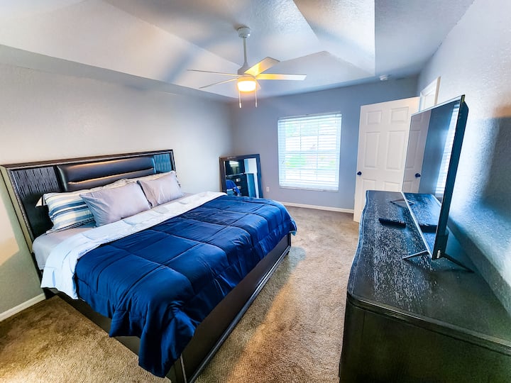 Dormitorio principal con cama tamaño king, TV, espejo, mesita de noche y baño en suite
