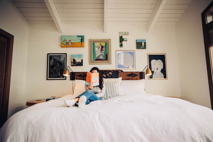 غرفة النوم الرئيسية التي تحتوي على سرير كبير ومنطقة جلوس مع نوافذ من الأرض إلى السقف هي المكان المثالي للقراءة والاستمتاع بالمناظر