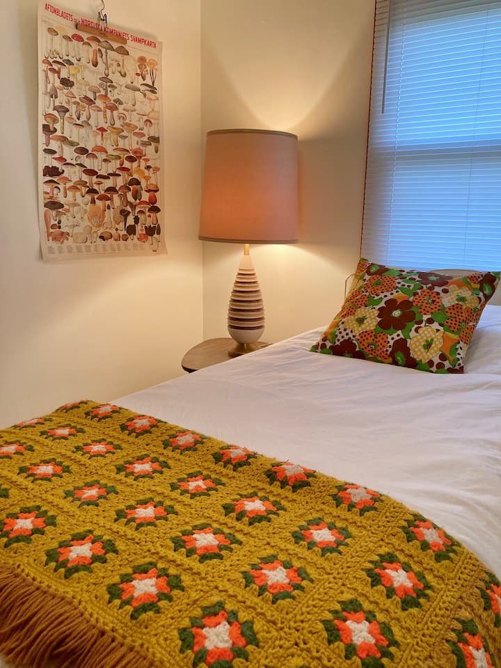 EL SEGUNDO DORMITORIO está amueblado con una cama doble, una almohada, edredón, manta, mesita de noche, una lámpara, una silla lateral, un armario, una alfombra, un armario con portaequipajes, almohadas adicionales, mantas y un armario. Un gabinete de curio tiene una selección de libros/juegos/rompecabezas.