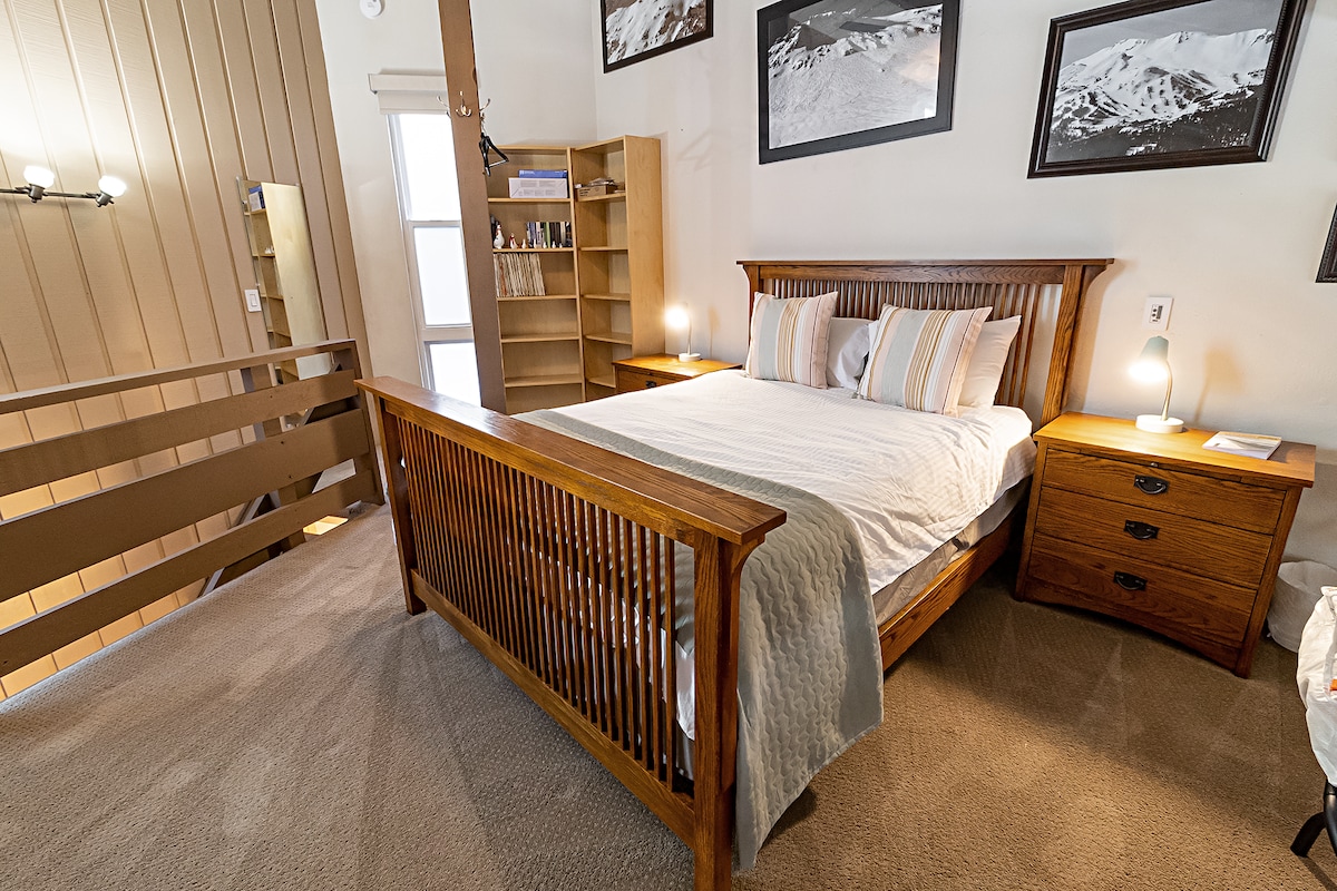 ห้องใต้หลังคาพร้อมเตียงควีนไซส์และโต๊ะกลางคืน 