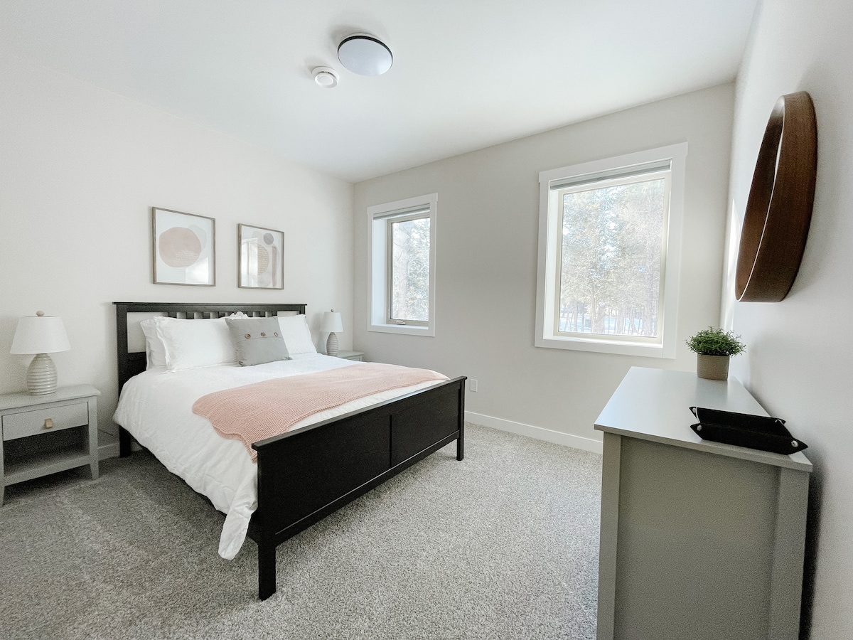 Priestranná spálňa s manželskou posteľou Queen a výhľadom na les.