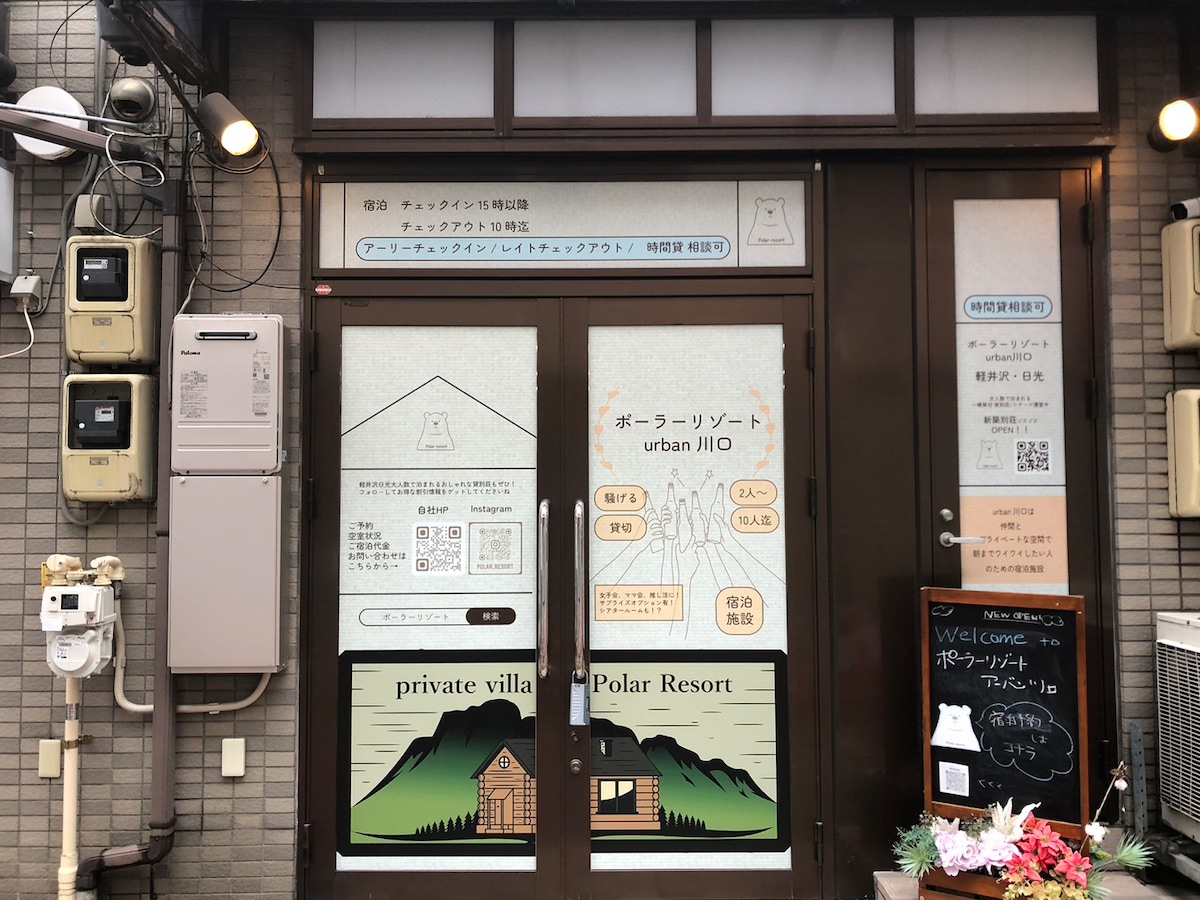 The entrance to the private villa is displayed with large glass doors featuring an illustration of a mountain and trees. Informational signs and notices are affixed to the door, providing details about the property. Utility meters are visible to the side.