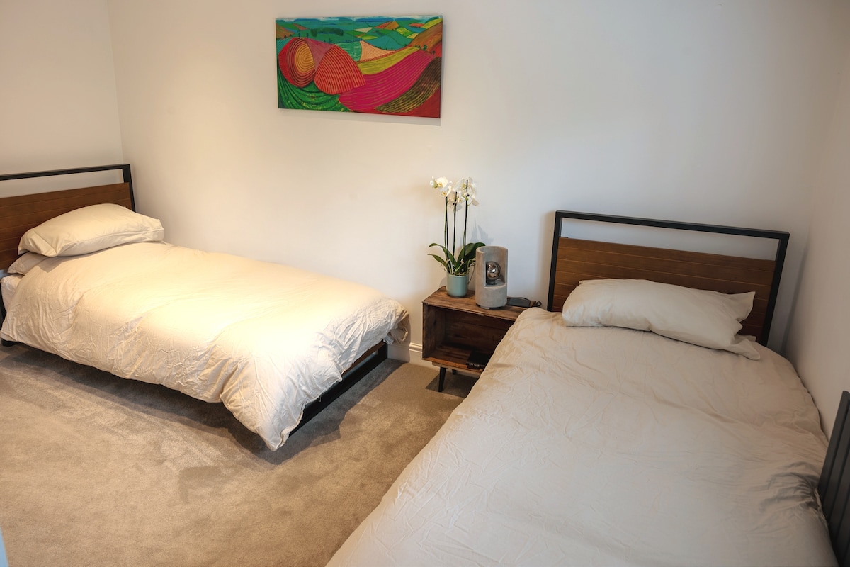 Prostrana druga spavaća soba u obliku slova L s dva kreveta za jednu osobu, s nagrađivanim Evi madracima i egipatskom pamukom.