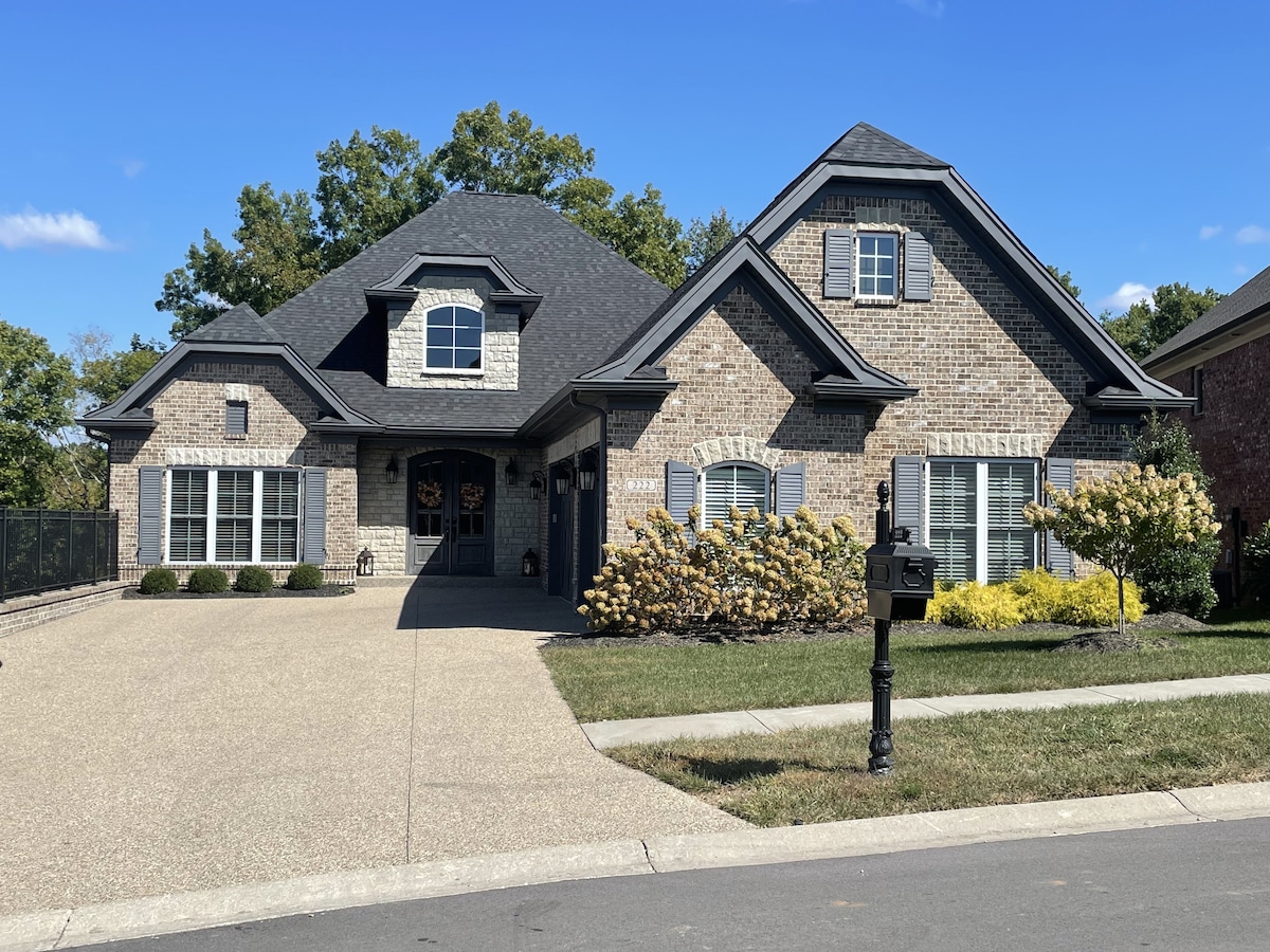 The exterior of the home is showcased with a well-maintained brick facade and a pitched roof. A spacious driveway leads to the entrance, framed by manicured landscaping and shrubs. A decorative mailbox stands in front, completing the welcoming appearance.