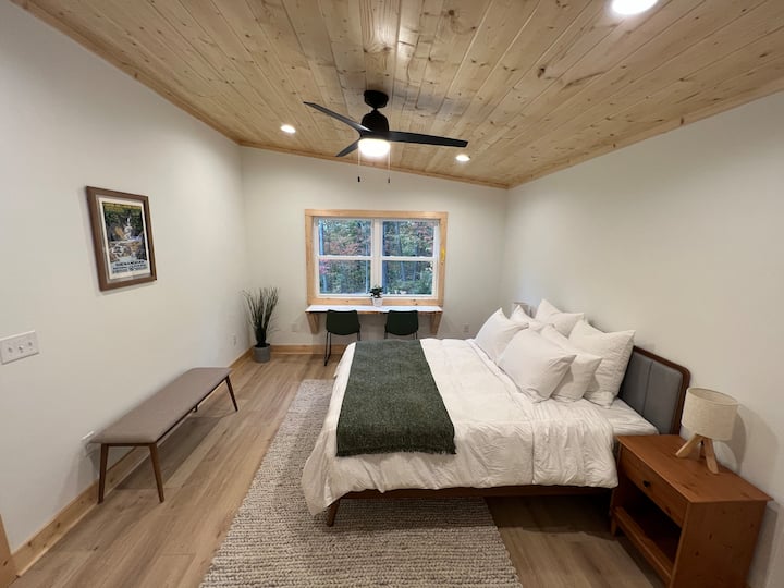 Chumba cha wageni cha kisasa, cha kifahari kilicho na kitanda cha malkia na mashuka ya starehe.