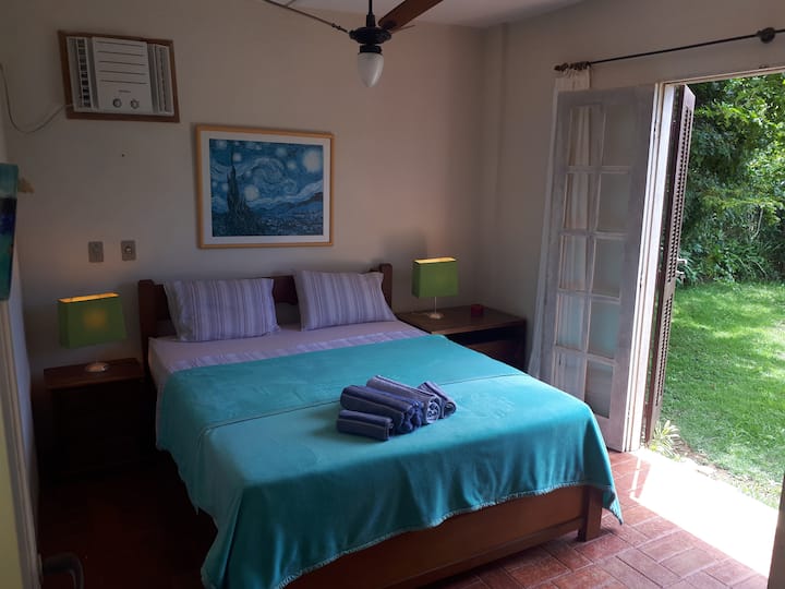 Suite 1 (planta baja), cama queen, aire acondicionado y ventilador de techo (puerta con integración a la zona verde)