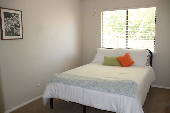 Dormitorio soleado con cama tamaño queen.