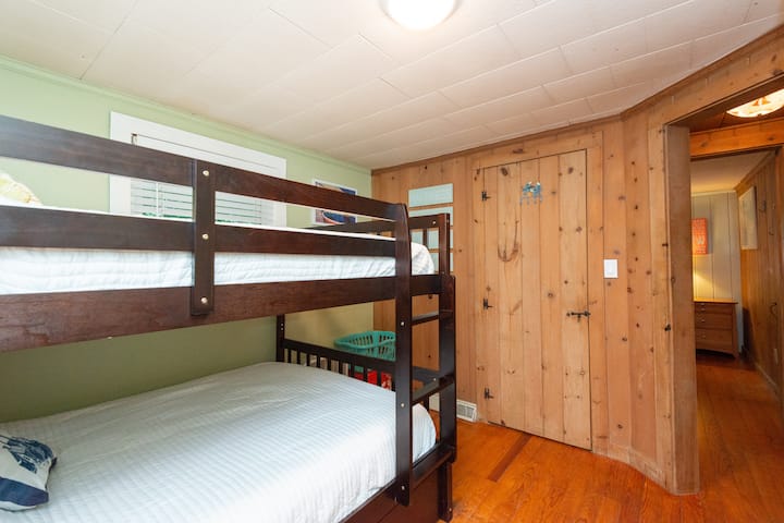 Bedroom 2 with full- sized bunk beds, 2 windows, box fan, dimmable ceiling light, closet, bureau, hamper, small side table, clean linens. 