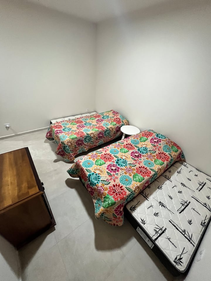 Suite 3 con 2 camas individuales que forman juntas una cama doble, armario y muebles pequeños.