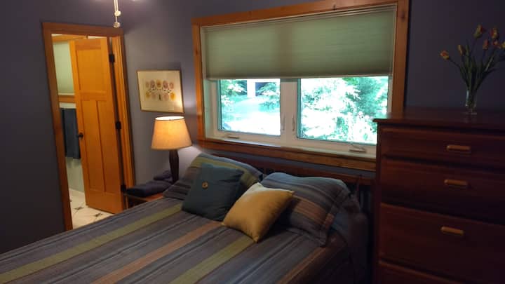 Primer piso, segundo dormitorio: suite queen, muebles de madera de cereza y baño privado de azulejos, ventilador de techo.