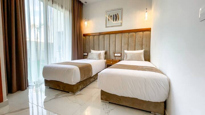 غرفة النوم الأولى في فيلا عليا مشرقة. يحتوي على سريرين مفردين وتلفزيون مع قنوات الكابل وخزانة تخزين لتخزين أمتعتك الشخصية.