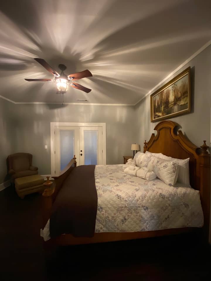 Relájate en este espacioso dormitorio principal con una gran cama, un acogedor sillón y una pantalla plana montada en la pared. Las puertas francesas se abren a un porche envolvente con mecedoras. Disfruta de acceso privado al baño principal para mayor comodidad y conveniencia.