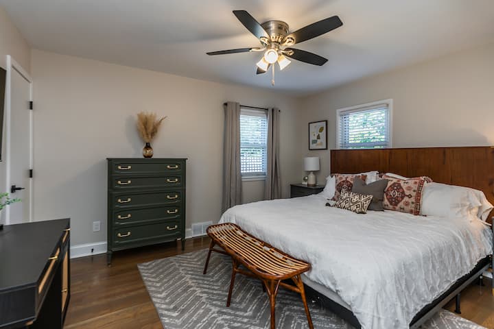 غرفة نوم بسرير كبير مع مروحة سقف وخزانة ملابس وخزانة ملابس وطاولات ليلية وخلفيات ومكتب وتلفزيون سامسونج سمارت مقاس 48بوصة