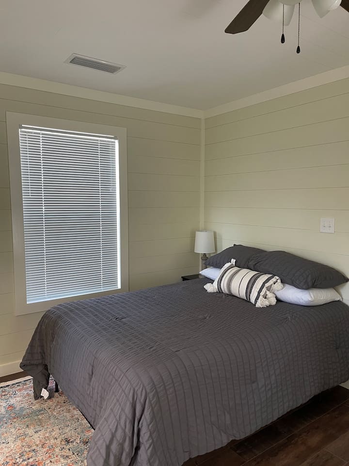 تحتوي غرفة النوم على سرير كامل الحجم بما في ذلك حامل ليلي مع رفوف ومصباح. 