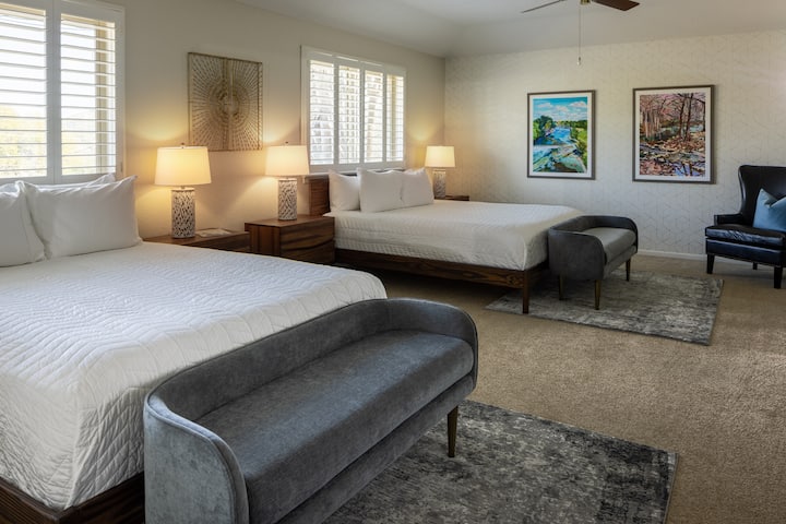 Amplio dormitorio con dos camas tamaño king y escritorio con silla de oficina. Separadores de privacidad de madera disponibles para colocar entre camas, para mayor privacidad. Además, tenemos una cuna grande disponible para esta habitación. Y disfruta del arte local en cada dormitorio y hogar.