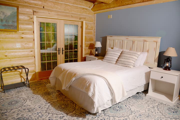 Hauptschlafzimmer mit Doppelbett und französischen Türen, die zu einer abgeschirmten Veranda führen.