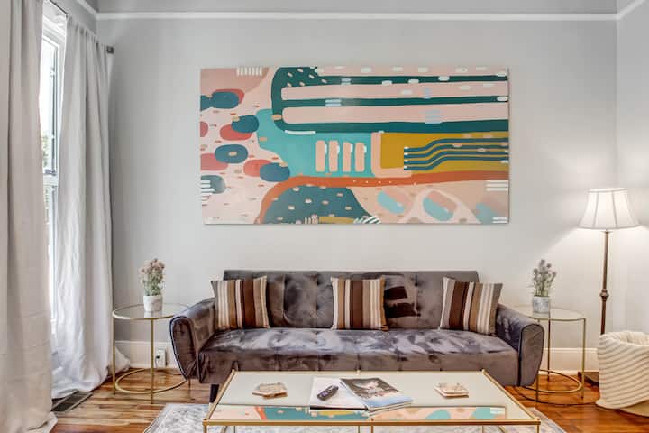 1st Floor - The living room of this newly furnished home features original art, large windows for plenty of natural light, and a full-size sleeper sofa.