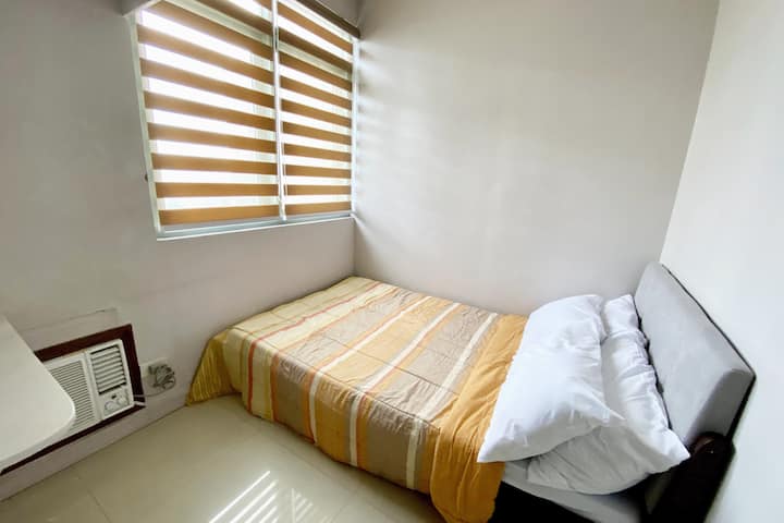 ห้องนอน 2 พร้อมเตียงคู่และเครื่องปรับอากาศแบบหน้าต่าง วิวทิวทัศน์คือโรบินสันมะนิลา