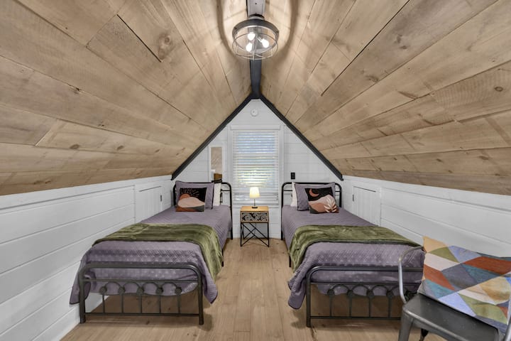 The loft contains two twin beds and a cozy reading spot. The window has a blind. In warmer months a portable air conditioner is between the beds. There are stand fans as well.