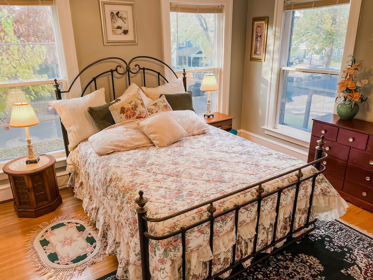 Chumba kikubwa cha kulala cha ghorofa ya pili kilichowekwa vizuri na kitanda kizuri cha ukubwa wa malkia na mwanga mwingi wa asili.