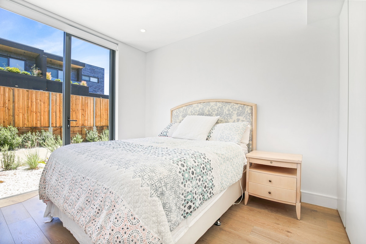 Amplio dormitorio en la planta baja con una cama tamaño queen, dos mesitas de noche, un tocador y un armario extra grande. Hermosa iluminación con ventana extra grande.