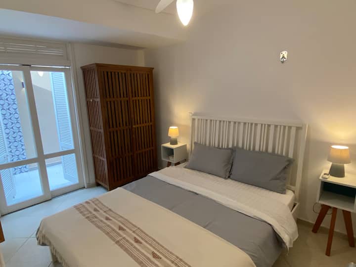 Vista del baño privado, con una puerta corrediza a la zona exterior, armario, perchero y cama tamaño queen.