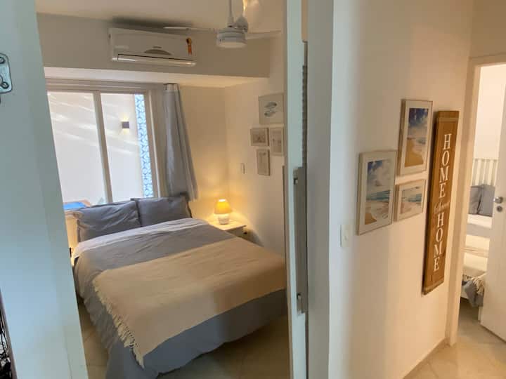 Vista del pasillo a las habitaciones. A la izquierda, dormitorio doble con armario, percha, espejo y aire acondicionado y ventilador de techo. Puerta corrediza. 