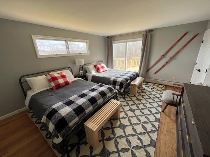 Guest room on main floor with two queens beds and a sliding door to walkout to deck.