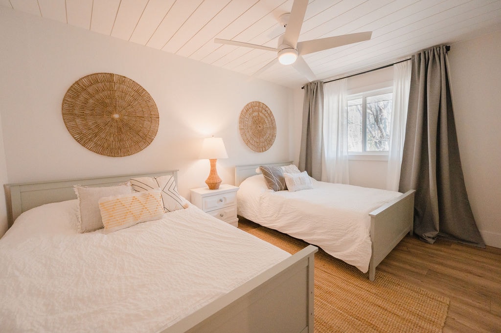 Spálňa na hornom poschodí s dvoma manželskými posteľami, stropným ventilátorom a veľkým šatníkom.