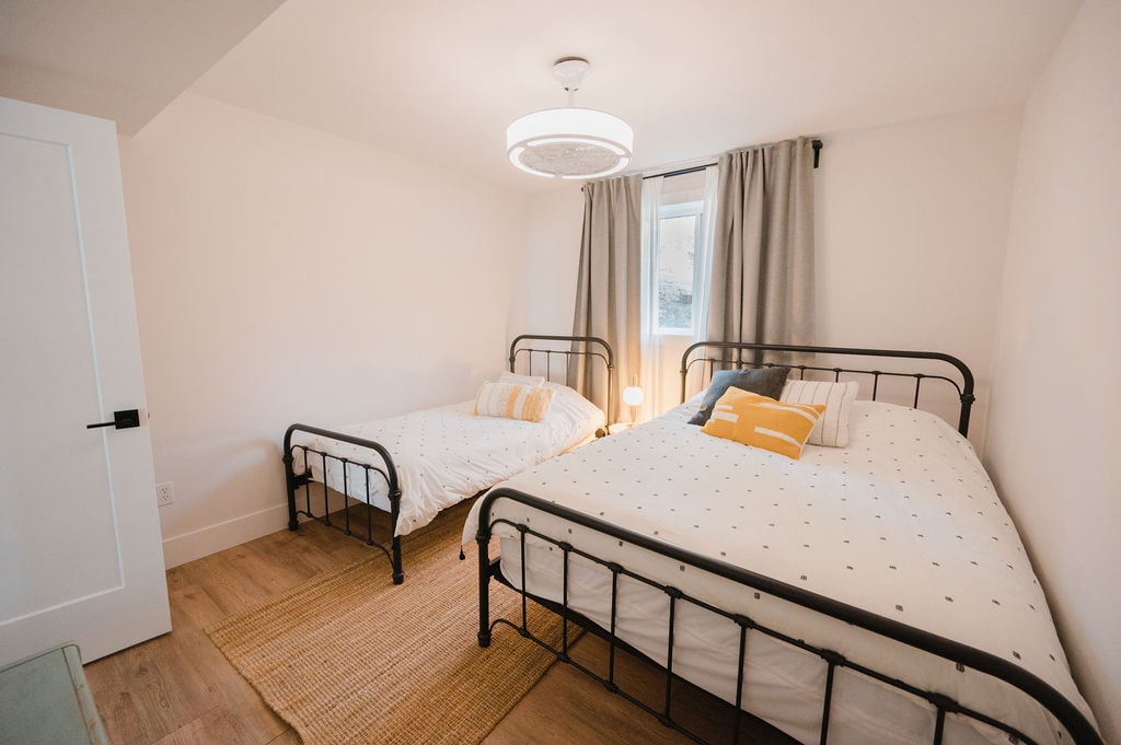 Spálňa na nižšej úrovni s jednou manželskou posteľou a jedným dvojčaťom, stropným ventilátorom a veľkým oknom na svetlo.