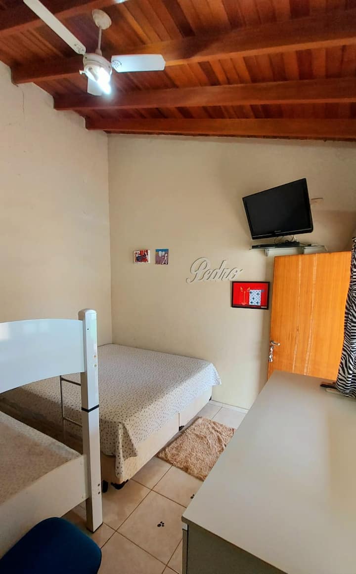 1号室、スイートのスーパーキングサイズのベッド1台、2段ベッド、テレビ、窓のエアコン、扇風機。