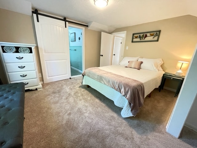 Pink bedroom hosts an en-suite. The bedroom has a tall oscillating fan, beautiful bench and dresser. The bathroom has the original green tile yet a modern sink and light up mirror.
