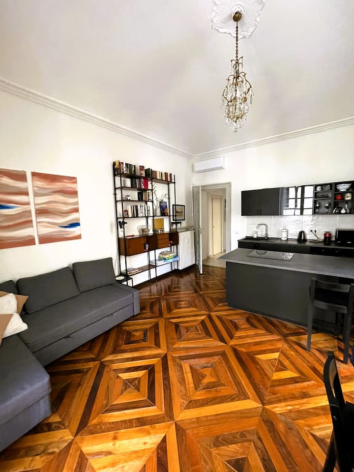 Ampio soggiorno dove gli alti soffitti a volta ed il pavimento in legno conferiscono fascino e atmosfera;  dotato di cucina ad isola completamente attrezzata, divano letto, libreria, smart TV, aria condizionata