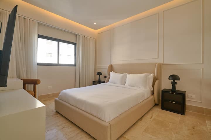 La habitación de nuestro apartamento en la Torre Ducal está diseñada para ofrecerte comodidad y funcionalidad. Tiene una elegante cama tamaño queen, vestida con tela de lino suave, lo que garantiza un descanso agradable. Disfruta del entretenimiento y la relajación con un televisor de 55 pulgadas.