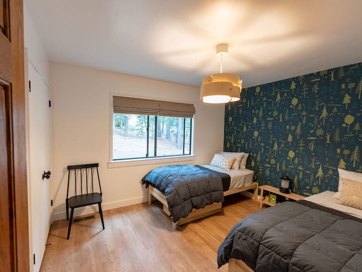 Set against a backdrop of hand-screenprinted wallpaper from Makelike Studio, the second bedroom overlooks a wooded lot, providing lots of privacy between homes. The two x-large twin beds convert easily to a king.