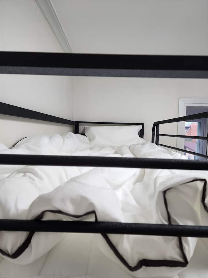 Katika chumba cha ukubwa wa kati, kuna dawati kwenye ghorofa ya kwanza na vitanda viwili vya ghorofa kwenye ghorofa ya pili. Kuna uchangamfu unaotoa nafasi, na inafaa.