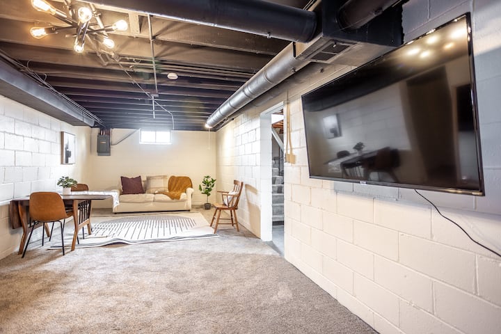 Settle into the lower-level lounge — a cozy retreat with a large TV, soft carpet, and space to unwind. Connected to a bedroom, bathroom, and laundry, it’s perfect for movie nights or quiet mornings with coffee.Large sectional sleeping sofa.
