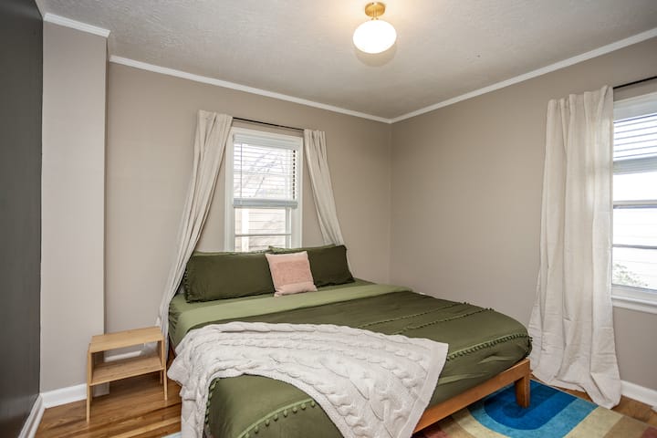 Rest easy in this spacious main-floor bedroom featuring a plush king bed, nightstands, and a full closet with hangers for your stay. Room-darkening shades ensure a peaceful night’s sleep, making it the perfect spot to recharge.