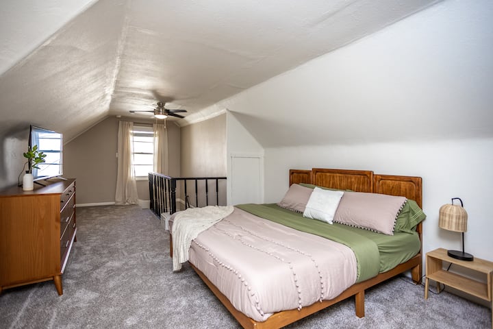 Retreat upstairs to your private getaway featuring a large  king bed, smart TV, and dresser for easy storage. The soft lighting and sloped ceilings create a peaceful, tucked-away feel. Enjoy a bathroom with a walk-in shower and an additional bedroom.