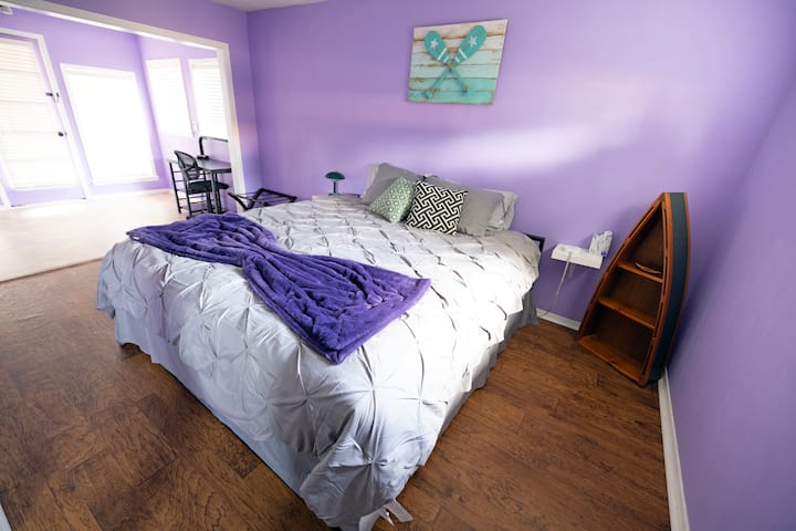 Private master bedroom with a king bed, closet, clothing rack and office work space. 