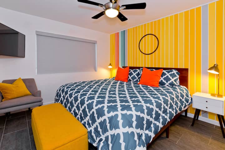 Guest King Bedroom with large mirrored closet, dresser, ceiling fan, Smart TV, bedside charging ports and blackout roller shades.
