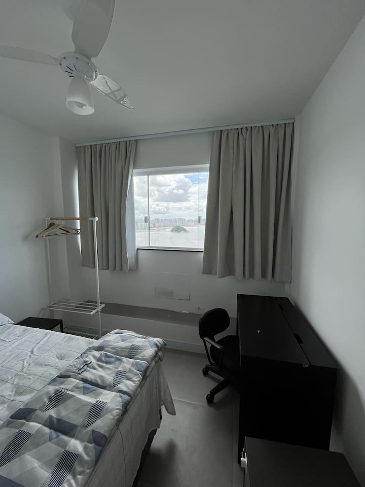 غرفة بسرير مزدوج ورف ملابس ومكتب للعمل. ستارة سوداء.