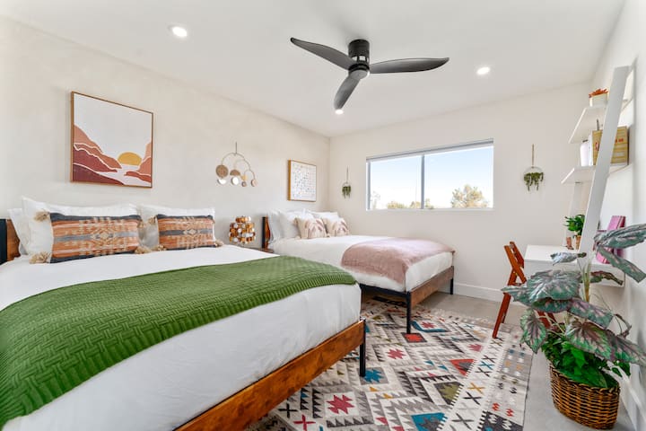 غرفة نوم ثالثة بسريرين متوسطي الحجم وفن صحراوي وسجادة بوهيمية