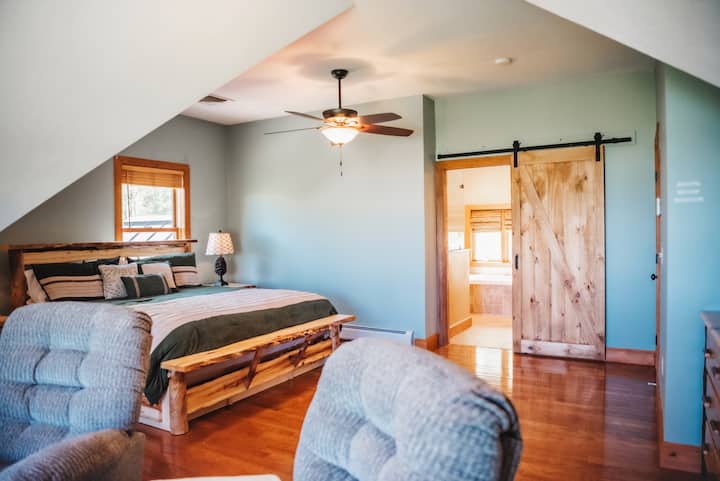 Our spacious bedrooms feature beautiful wood features such as this barn door, and cabin-inspired furnishings, enhancing the overall woodsy ambiance.