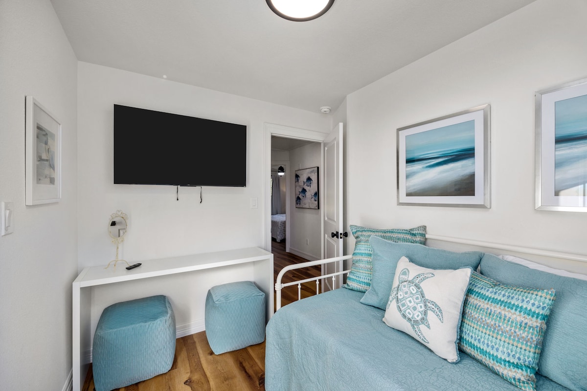 Гледајќи кон ходникот од втората спална соба, можете да ги видите 50-инчниот паметен телевизор и маса со огледало и седишта за подготовка за денот.