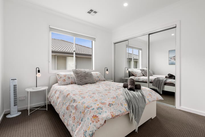 This bright and welcoming bedroom features a plush queen-sized bed, mirrored built-in wardrobes, and soft natural light, perfect for a peaceful night's sleep