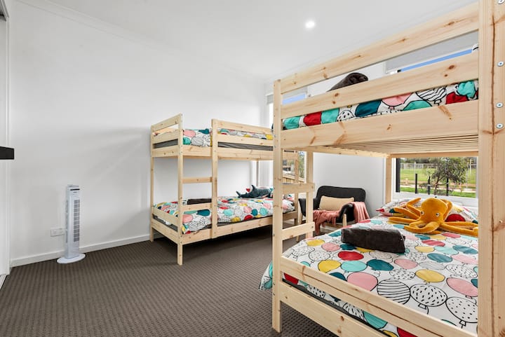 Designed with kids in mind, this playful bedroom features two sets of bunk beds, vibrant bedding, plush toys, and a cosy reading chair—all overlooking a peaceful, green outlook