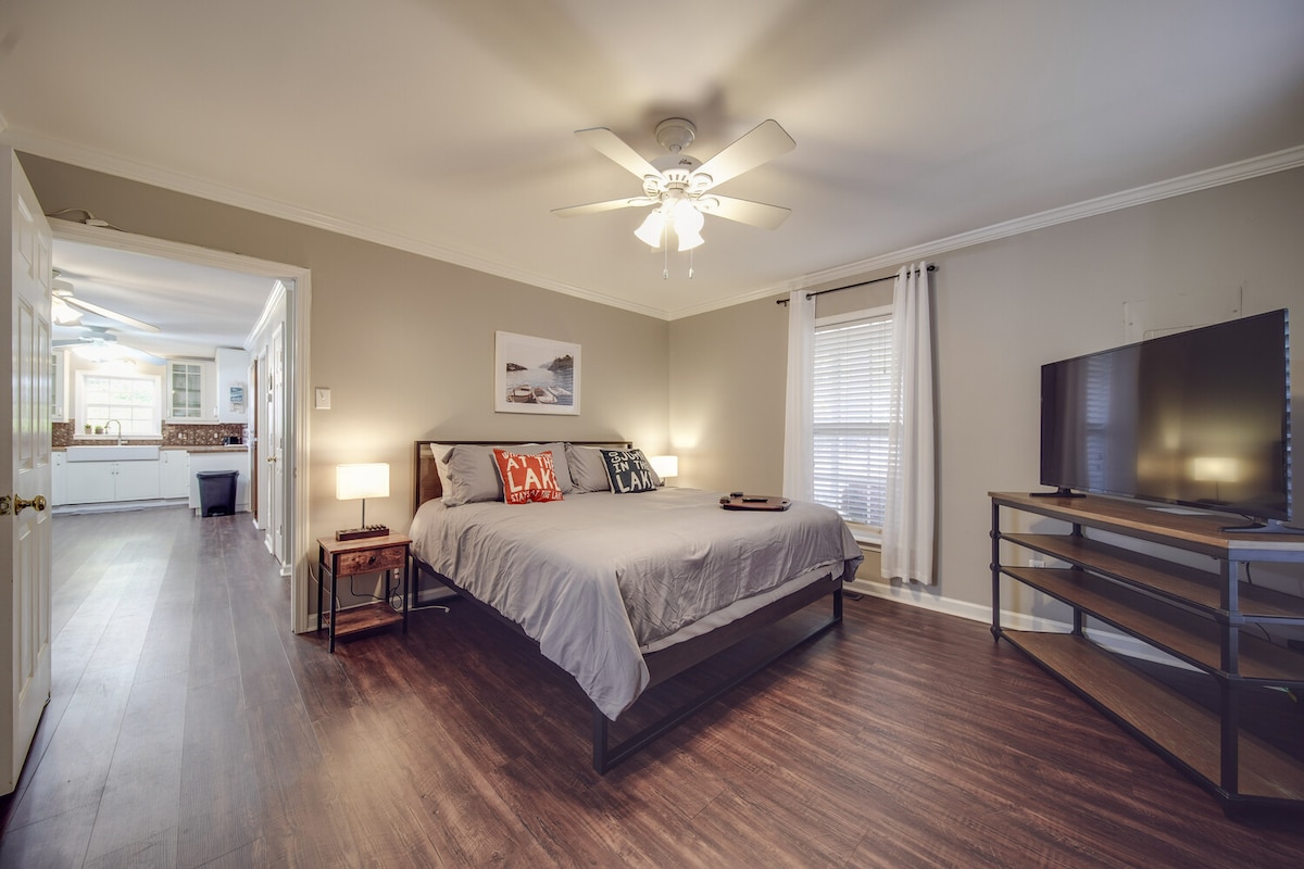 Kitanda cha mfalme katika chumba cha kulala cha msingi kilicho na runinga na kabati kubwa la kuingia na kutoka.