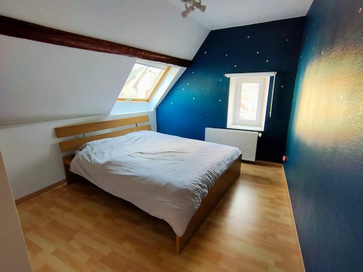 The blue bedroom and its Queen Bed.
From the pillows we have a view of the church clock through the velux.

(The wall is full of decenterous stars. It's so cool.)
